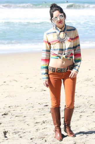 Модный лук: разноцветная классическая рубашка в горизонтальную полоску, оранжевые джинсы скинни, коричневые кожаные сапоги, розовые солнцезащитные очки