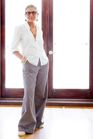 С чем носить серебряные широкие брюки: Белая классическая рубашка в паре с серебряными широкими брюками позволит составить модный и элегантный лук. Любительницы смелых вариантов могут дополнить наряд бежевыми слипонами.