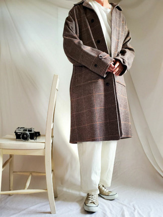 С чем носить темно-коричневое пальто мужчине весна в стиле кэжуал: Темно-коричневое пальто в паре с белыми брюками чинос — нескучный вариант для парней, работающих в офисе. Завершив образ светло-коричневыми низкими кедами из плотной ткани, можно привнести в него классическую нотку. Это сочетание прекрасно подходит для неустойчивой весенней погоды.