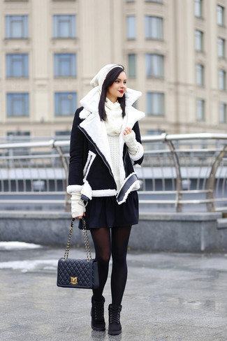 Модный лук: черно-белая короткая дубленка, белый свитер с круглым вырезом, черная короткая юбка-солнце, черные замшевые ботинки на шнуровке