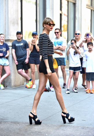 Как Taylor Swift носит Темно-сине-белый короткий свитер в горизонтальную полоску, Черные шорты, Черные кожаные массивные босоножки на каблуке, Желтая кожаная сумочка
