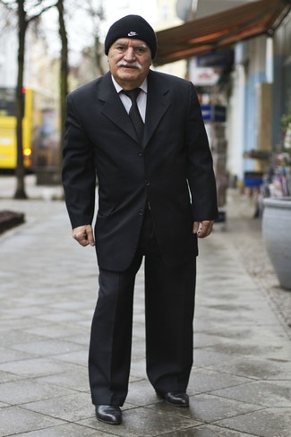 С чем носить черную шапку за 60 лет мужчине в теплую погоду в деловом стиле: Если ты любишь одеваться с иголочки, и при этом чувствовать себя комфортно и уверенно, попробуй это сочетание черного костюма и черной шапки. Такой лук обретает новое прочтение в сочетании с черными кожаными ботинками челси.