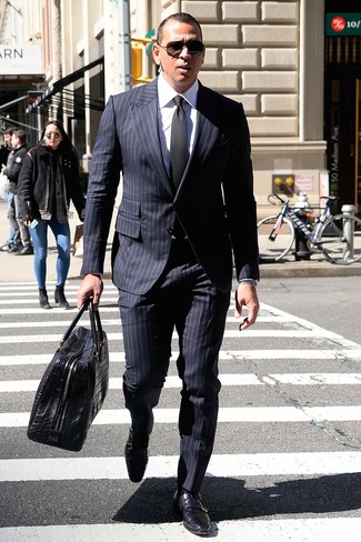 Темно-синий костюм в вертикальную полоску и белая классическая рубашка — великолепный пример изысканного мужского стиля в одежде. Пара черных кожаных монок с двумя ремешками легко вписывается в этот образ.