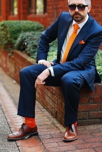 С чем носить оранжевый галстук за 40 лет мужчине в деловом стиле: Несмотря на то, что это довольно сдержанный ансамбль, сочетание темно-синего костюма и оранжевого галстука приходится по вкусу джентльменам, пленяя при этом дамские сердца. Ну и почему бы не разбавить лук с помощью коричневых кожаных оксфордов?