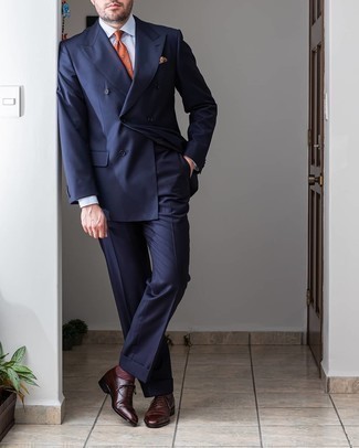 Как носить темно-синий костюм с оранжевым галстуком в теплую погоду: Несмотря на то, что этот образ кажется довольно-таки выдержанным, дуэт темно-синего костюма и оранжевого галстука всегда будет нравиться стильным мужчинам, непременно покоряя при этом сердца прекрасных дам. Поклонники незаезженных вариантов могут завершить образ темно-коричневыми кожаными оксфордами.