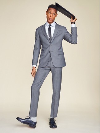 С чем носить темно-синий галстук в вертикальную полоску мужчине в деловом стиле: Серый костюм выглядит гармонично в паре с темно-синим галстуком в вертикальную полоску. Такой лук несложно адаптировать к повседневным реалиям, если надеть в сочетании с ним темно-синие кожаные туфли дерби.