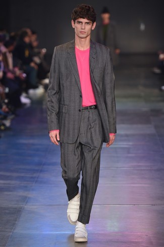 Модный лук: серый костюм в вертикальную полоску, ярко-розовый свитер с круглым вырезом, белые кожаные низкие кеды, черный кожаный ремень