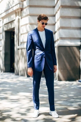 С чем носить темно-синие солнцезащитные очки в 20 лет мужчине: Если ты ценишь удобство и практичность, обрати внимание на это дуэт синего костюма в вертикальную полоску и темно-синих солнцезащитных очков. Пара белых низких кед из плотной ткани поможет сделать образ более законченным.