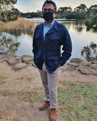 С чем носить темно-синюю куртку в стиле милитари за 50 лет мужчине в стиле смарт-кэжуал: Темно-синяя куртка в стиле милитари и бежевые брюки чинос — неотъемлемые предметы в гардеробе парней с замечательным вкусом в одежде. В тандеме с этим образом наиболее уместно смотрятся коричневые замшевые ботинки дезерты.