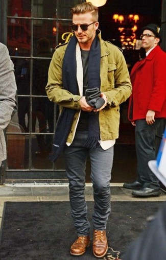 Как David Beckham носит Оливковая куртка в стиле милитари, Оливковая футболка с круглым вырезом, Серые зауженные джинсы, Коричневые кожаные туфли дерби
