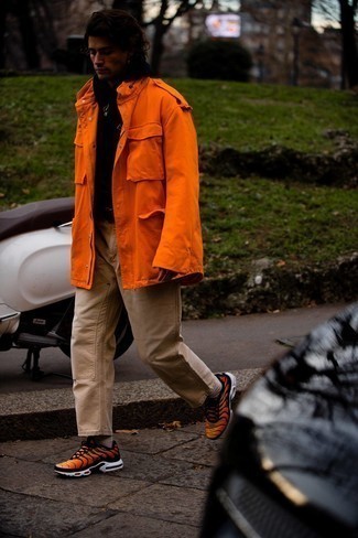 С чем носить оранжевую куртку в стиле милитари мужчине осень: Фанатам непринужденного стиля понравится сочетание оранжевой куртки в стиле милитари и светло-коричневых брюк чинос. Ты сможешь легко адаптировать такой образ к повседневным делам, дополнив его оранжевыми кроссовками. Разве это не классный выбор на межсезонье, когда столбик термометра неуклонно ползет вниз?