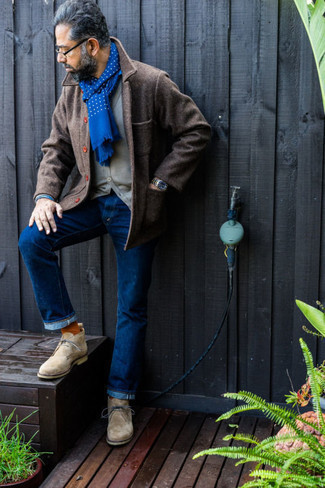 Как носить темно-серый кардиган с темно-синими джинсами за 50 лет мужчине в стиле смарт-кэжуал: Образ из темно-серого кардигана и темно-синих джинсов — превосходный пример современного городского стиля. Бежевые замшевые ботинки дезерты — отличный вариант, чтобы закончить образ.