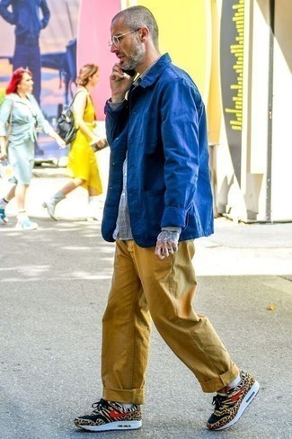 С чем носить золотые джинсы мужчине в теплую погоду в стиле кэжуал: Синяя куртка-рубашка и золотые джинсы — неотъемлемые вещи в гардеробе парней с чувством стиля. Поклонники рискованных вариантов могут завершить образ светло-коричневыми низкими кедами с леопардовым принтом.