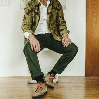 Как носить темно-зеленые джинсы с бежевыми замшевыми ботинками дезертами: Оливковая куртка-рубашка с камуфляжным принтом в паре с темно-зелеными джинсами — замечательный вариант для создания мужского образа в стиле business casual. Весьма уместно здесь выглядят бежевые замшевые ботинки дезерты.