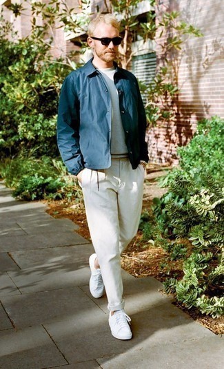 Как носить белые брюки чинос с бело-синими низкими кедами из плотной ткани в 30 лет в стиле смарт-кэжуал: Если ты принадлежишь к той категории парней, которые одеваются стильно, тебе подойдет дуэт темно-синей нейлоновой куртки-рубашки и белых брюк чинос. Пара бело-синих низких кед из плотной ткани добавит ансамблю непринужденности и динамичности.