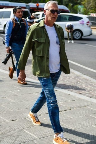 С чем носить оливковую куртку-рубашку мужчине: Если ты любишь смотреться с иголочки, чувствуя себя при этом комфортно и расслабленно, попробуй это сочетание оливковой куртки-рубашки и синих джинсов в стиле пэчворк. Почему бы не привнести в этот образ толику расслабленности с помощью табачных низких кед из плотной ткани?