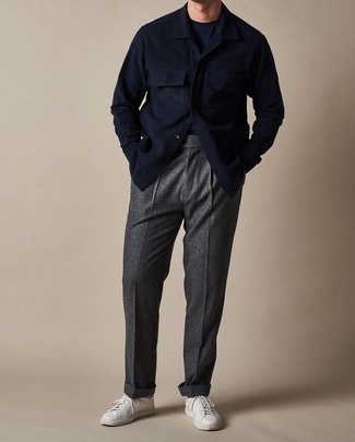 С чем носить темно-серые шерстяные классические брюки мужчине в стиле смарт-кэжуал: Темно-синяя шерстяная куртка-рубашка в сочетании с темно-серыми шерстяными классическими брюками — великолепный пример делового городского стиля. Почему бы не привнести в этот ансамбль толику легкой небрежности с помощью белых низких кед из плотной ткани?