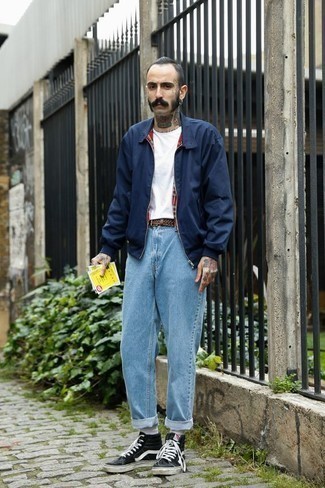 С чем носить голубые джинсы в 30 лет мужчине в теплую погоду: Если ты ценишь удобство и практичность, обрати внимание на лук из темно-синей куртки харрингтон и голубых джинсов. Чтобы образ не получился слишком зализанным, можно завершить его черно-белыми высокими кедами из плотной ткани.