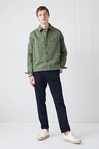Как носить темно-зеленую куртку-рубашку с бело-синими низкими кедами из плотной ткани мужчине: Комбо из оливковой куртки-рубашки и темно-синих брюк чинос — необыденный образ для парней, работающих в офисе.