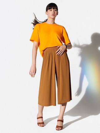 С чем носить брюки женщине в жару: Оранжевая футболка с круглым вырезом и брюки помогут создать несложный и практичный образ для выходного в парке или торговом центре. Табачные замшевые босоножки на каблуке станут превосходным дополнением к твоему луку.