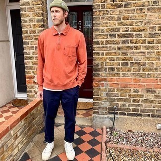 Модный лук: оранжевый свитер с воротником поло, темно-синие брюки чинос, белые высокие кеды из плотной ткани, оливковая шапка