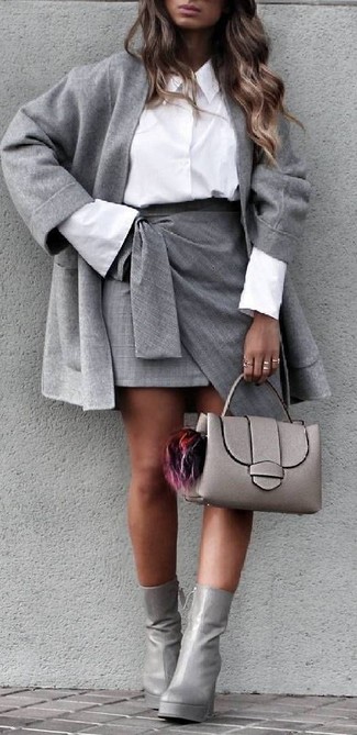 С чем носить серое пальто в 30 лет женщине в деловом стиле: Ансамбль из серого пальто и серой мини-юбки с разрезом позволит создать интересный наряд в расслабленном стиле. Очень уместно здесь будут выглядеть серые кожаные ботильоны.