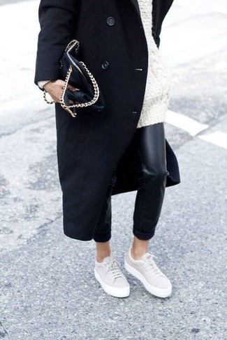 Модный лук: черное пальто, белый вязаный свободный свитер, черные кожаные узкие брюки, бежевые низкие кеды