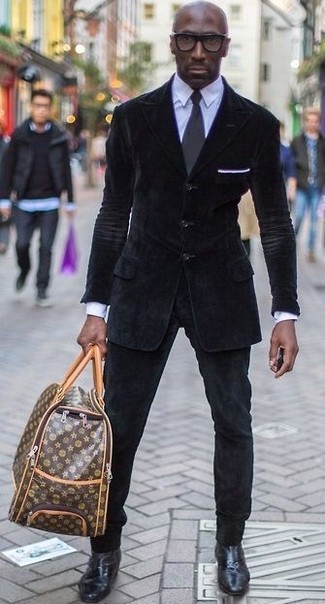 С чем носить темно-коричневую кожаную дорожную сумку с принтом мужчине в теплую погоду в стиле смарт-кэжуал: Сочетание черного вельветового пиджака и темно-коричневой кожаной дорожной сумки с принтом - очень практично, и поэтому прекрасно подойдет для воплощения интересного повседневного стиля. Очень неплохо здесь будут смотреться черные кожаные ботинки челси.
