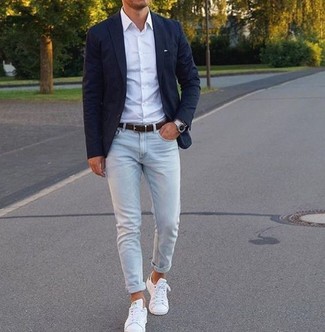 Как носить зауженные джинсы с низкими кедами в 30 лет мужчине в стиле смарт-кэжуал: Дуэт темно-синего пиджака и зауженных джинсов — отличный пример современного стиля в большом городе. В сочетании с этим луком наиболее уместно будут выглядеть низкие кеды.