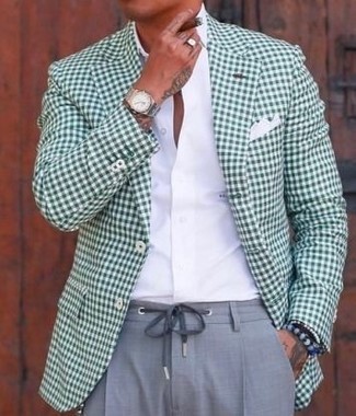 С чем носить зеленый пиджак мужчине в теплую погоду: Зеленый пиджак в паре с серыми классическими брюками — замечательный пример делового городского стиля.