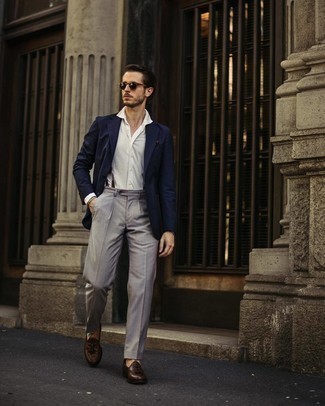 Как носить темно-синий пиджак с серыми классическими брюками мужчине лето: Темно-синий пиджак в паре с серыми классическими брюками позволит создать запоминающийся мужской лук. Вкупе с этим образом идеально смотрятся темно-коричневые кожаные лоферы с кисточками. Подобный образ несомненно будет у тебя одним из самых любимых в жаркие солнечные деньки.