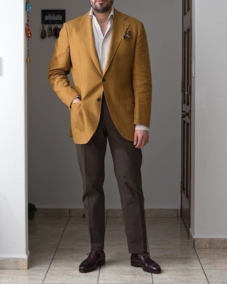 С чем носить табачные классические брюки мужчине в теплую погоду: Желтый пиджак в сочетании с табачными классическими брюками поможет создать эффектный мужской лук. Вкупе с этим ансамблем гармонично смотрятся темно-красные кожаные туфли дерби.