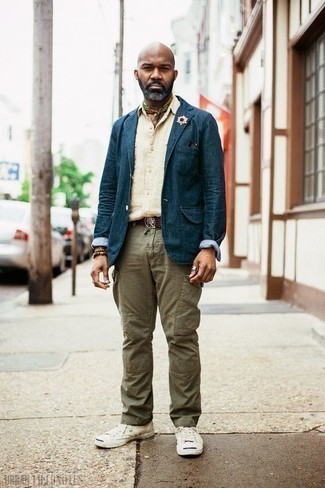 С чем носить джинсовый пиджак за 40 лет мужчине: Если на работе у тебя довольно демократичный дресс-код, обрати внимание на это тандем джинсового пиджака и оливковых брюк карго. Ты сможешь легко приспособить такой лук к повседневным реалиям, завершив его белыми низкими кедами из плотной ткани.