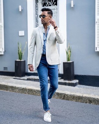 Как носить серый пиджак с синими джинсами мужчине в стиле кэжуал: Сочетание серого пиджака и синих джинсов — интересный вариант для рабочего дня в офисе. Поклонники смелых вариантов могут закончить лук белыми низкими кедами из плотной ткани.