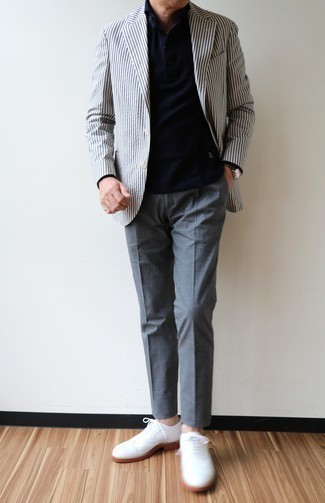 С чем носить бело-темно-синий пиджак в вертикальную полоску мужчине в деловом стиле: Несмотря на то, что этот образ выглядит довольно-таки сдержанно, тандем бело-темно-синего пиджака в вертикальную полоску и серых классических брюк всегда будет по вкусу стильным мужчинам, неминуемо пленяя при этом дамские сердца. Белые кожаные броги — идеальный выбор, чтобы закончить лук.
