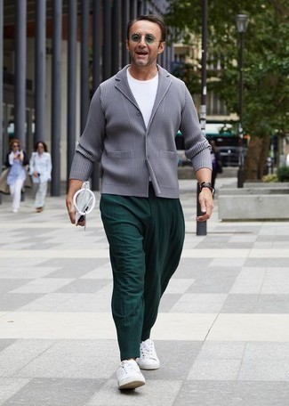 С чем носить темно-зеленые брюки чинос за 40 лет в теплую погоду в стиле кэжуал: Серый пиджак в паре с темно-зелеными брюками чинос — олицетворение непринужденного офисного стиля для джентльменов. Этот лук великолепно дополнят белые низкие кеды из плотной ткани.