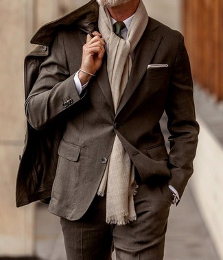 С чем носить коричневую кожаную полевую куртку в теплую погоду в деловом стиле: Коричневая кожаная полевая куртка в паре с темно-коричневым костюмом — воплощение делового городского стиля.