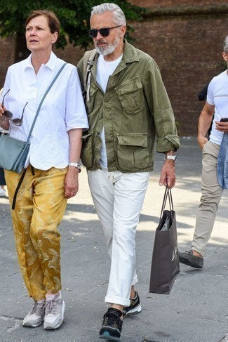 С чем носить футболку за 50 лет мужчине в стиле кэжуал: Сочетание футболки и белых брюк чинос не прекращает импонировать парням, которые всегда одеты со вкусом. Очень кстати здесь выглядят оливковые кроссовки.