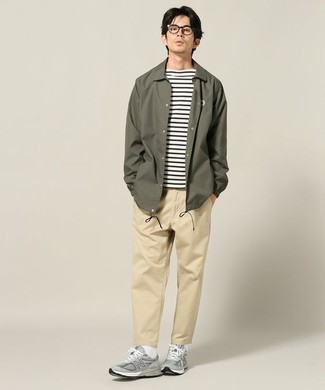 Модный лук: оливковая полевая куртка, бело-черная футболка с круглым вырезом в горизонтальную полоску, светло-коричневые брюки чинос, серые кроссовки