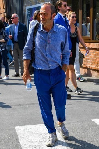 С чем носить синие брюки чинос за 50 лет в стиле кэжуал: Синяя льняная рубашка с длинным рукавом и синие брюки чинос прочно закрепились в гардеробе многих мужчин, помогая создавать неприевшиеся и удобные образы. Такой образ несложно приспособить к повседневным нуждам, если дополнить его серыми кроссовками.