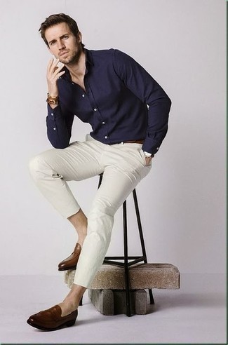 Модный мужской лук: темно-синяя рубашка с длинным рукавом, белые брюки чинос, коричневые кожаные лоферы, темно-коричневый кожаный ремень