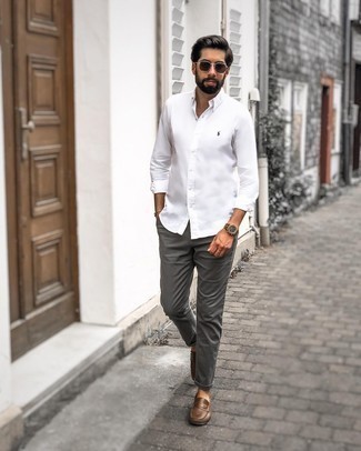 С чем носить мокасины в 30 лет мужчине в стиле кэжуал: Тандем белой рубашки с длинным рукавом и темно-серых брюк чинос позволит реализовать в твоем образе городской стиль современного молодого человека. Мокасины отлично дополнят этот лук.