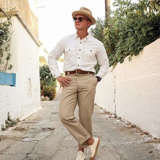 Модный лук: белая рубашка с длинным рукавом, светло-коричневые брюки чинос, белые низкие кеды из плотной ткани, бежевая соломенная шляпа