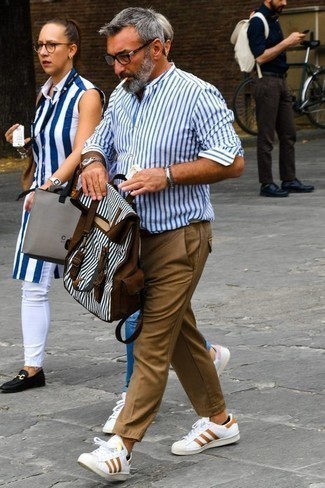 Как носить бело-синюю рубашку с длинным рукавом в вертикальную полоску с белыми низкими кедами за 50 лет мужчине: Бело-синяя рубашка с длинным рукавом в вертикальную полоску и светло-коричневые брюки чинос прочно обосновались в гардеробе многих джентльменов, помогая составлять запоминающиеся и стильные ансамбли. Вкупе с этим образом органично смотрятся белые низкие кеды.