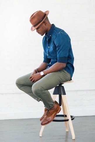 С чем носить темно-коричневую шляпу в 30 лет мужчине: Если в одежде ты ценишь удобство и практичность, синяя рубашка с длинным рукавом из шамбре и темно-коричневая шляпа — превосходный выбор для привлекательного мужского образа на каждый день. Опасаешься выглядеть несерьезно? Дополни этот лук коричневыми кожаными оксфордами.