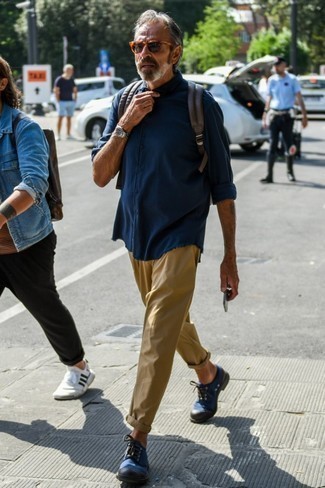 С чем носить темно-синюю рубашку за 50 лет мужчине в теплую погоду: Темно-синяя рубашка и светло-коричневые брюки чинос — классный вариант для несложного, но стильного мужского лука. Этот образ получает новое прочтение в тандеме с темно-синими туфлями дерби из плотной ткани.