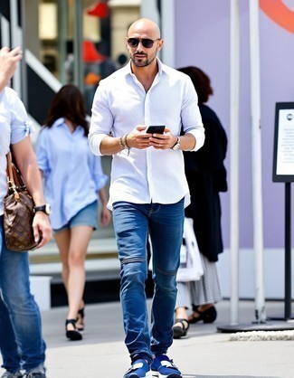 Модный мужской лук: белая рубашка с длинным рукавом, темно-синие джинсы, темно-синие кроссовки, темно-серые солнцезащитные очки