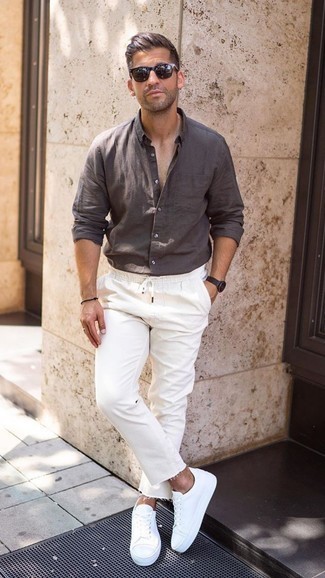Какие джинсы носить с белыми низкими кедами в 30 лет мужчине лето в стиле кэжуал: Темно-коричневая льняная рубашка с длинным рукавом и джинсы помогут составить свой неповторимый образ. Белые низкие кеды станут классным дополнением к твоему ансамблю. Пережить изнуряющий летний зной определенно легче, когда на тебе такое сочетание одежды.