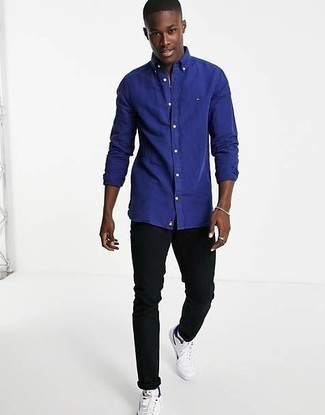 Модный лук: темно-синяя рубашка с длинным рукавом, черные джинсы, белые низкие кеды из плотной ткани, серебряный браслет