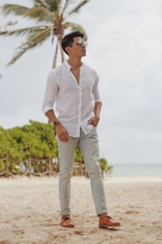 С чем носить темно-серые джинсы в 20 лет мужчине лето в стиле кэжуал: Белая льняная рубашка с длинным рукавом в сочетании с темно-серыми джинсами без сомнений будет обращать на себя взоры прекрасного пола. Вместе с этим ансамблем органично будут выглядеть светло-коричневые кожаные топсайдеры. Смело говорим, такое сочетание одежды - просто бомба в жаркий солнечный день.